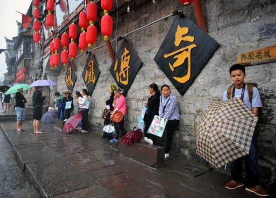 　4月29日上午11時20分，一些游客和古城當(dāng)?shù)氐木用穸阍谝粋€酒吧的屋檐下避雨。這些當(dāng)?shù)鼐用褚詾橛慰团恼罩\生，一場降雨讓他們的生意更加清淡。