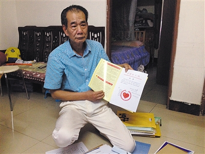 翻出一家網(wǎng)站贈予的“中國好人”證書，區(qū)少坤單膝跪在地上，“你看，我是中國好人啊。” 范春旭 攝
