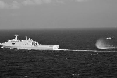 11日，抵達馬航飛機失聯海區的海軍井岡山艦與艦載直升機協同展開立體搜救行動。新華社發