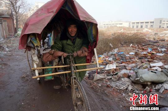 圖為老人走出窩棚，推著三輪車準(zhǔn)備出去撿拾廢品。周小云 攝