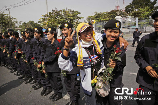 2013年12月03日,曼谷總理府與曼谷警署允許反政府示威民眾進(jìn)入,雙方進(jìn)入暫時(shí)“停戰(zhàn)”狀態(tài)迎接泰王生日。曼谷警察總署,女警們手持鮮花送給反政府示威民眾。圖片來源:Manish Swarup/東方IC