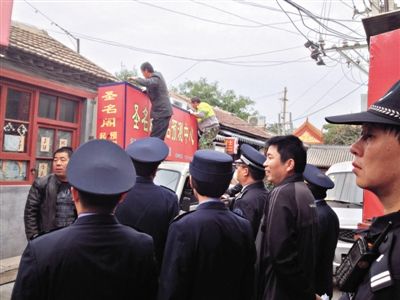 昨日下午,東城區(qū)工商、城管、公安等部門,對雍和宮附近的預(yù)測中心進行清理整頓,站在車頂?shù)膬擅と苏鸪患摇邦A(yù)測中心”的招牌。因雍和宮、白云觀等文化景點外聚集大量算命先生,被媒體稱為“算命一條街”。本版攝影/新京報記者 李寧 攝