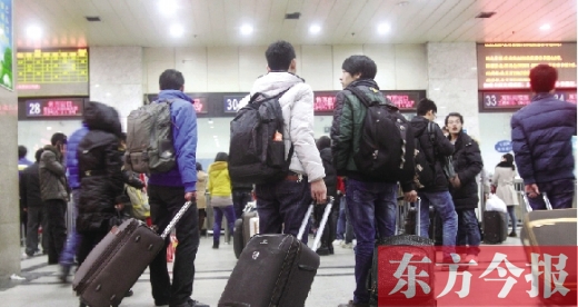 鄭州火車(chē)站東廣場(chǎng)售票大廳，幾名學(xué)生在售票窗口前躊躇
