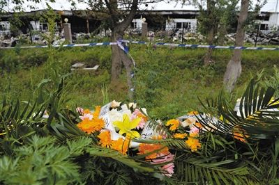 昨日，吉林省德惠市吉林寶源豐禽業有限公司燃燒事故現場警戒線外，遇難者家屬在路邊擺放了花圈祭奠逝去的親人。吳江 攝