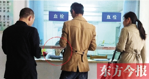 昨日，鄭州市二七區(qū)疾控中心辦證大廳，血檢窗口內(nèi)一名女工作人員，邊接受辦證者咨詢邊看報(bào)紙