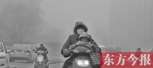 12月8日，鄭州市未來路上，一位市民帶著孩子在霧中騎行