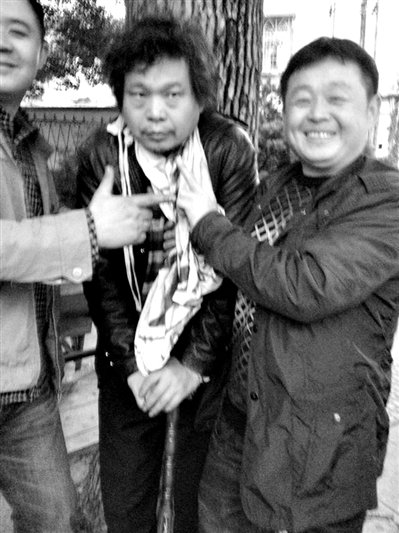 兩名接訪人員與患有癌癥的訪民段新德合影時(shí)，面帶笑容擺出勝利的手勢(shì)。