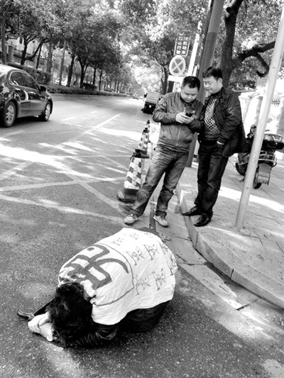 兩名接訪人員與患有癌癥的訪民段新德合影時(shí)，在拍照時(shí)查看手機(jī)。