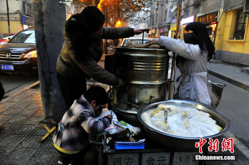 男孩西安路燈下寫作業 媽媽邊賣紅薯邊輔導
