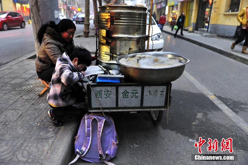 男孩西安路燈下寫作業 媽媽邊賣紅薯邊輔導