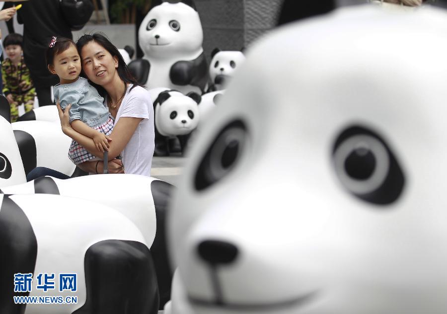 6月2日，一位家長(zhǎng)帶著孩子在上海街頭和大熊貓模型合影。
