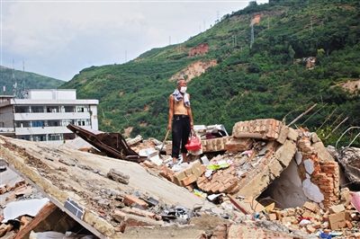 8月9日,龍頭山鎮,一位老者在自家房屋廢墟上尋找家當。