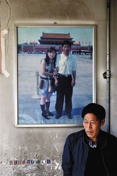 11月14日，承德市平泉縣，潘小梅父母的家，潘小梅父親靠在墻上，身后掛著數年前他和潘小梅在北京的合影照片。新京報記者