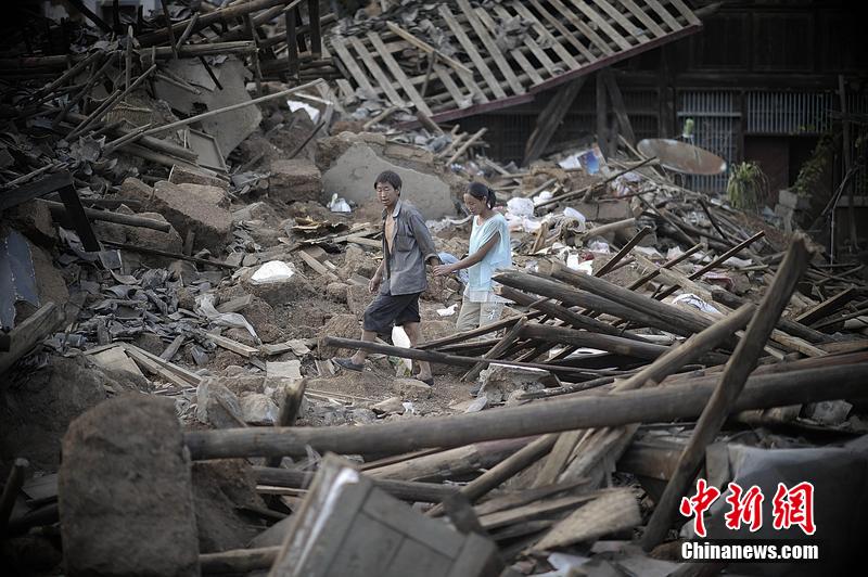 2014年8月5日，云南昭通龍頭山鎮(zhèn)老街，一對(duì)夫妻從居住房屋的廢墟中走過(guò)。