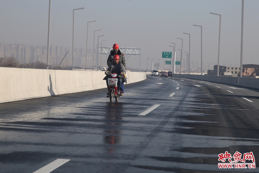 兩名工人騎車經過灑水養護路面。