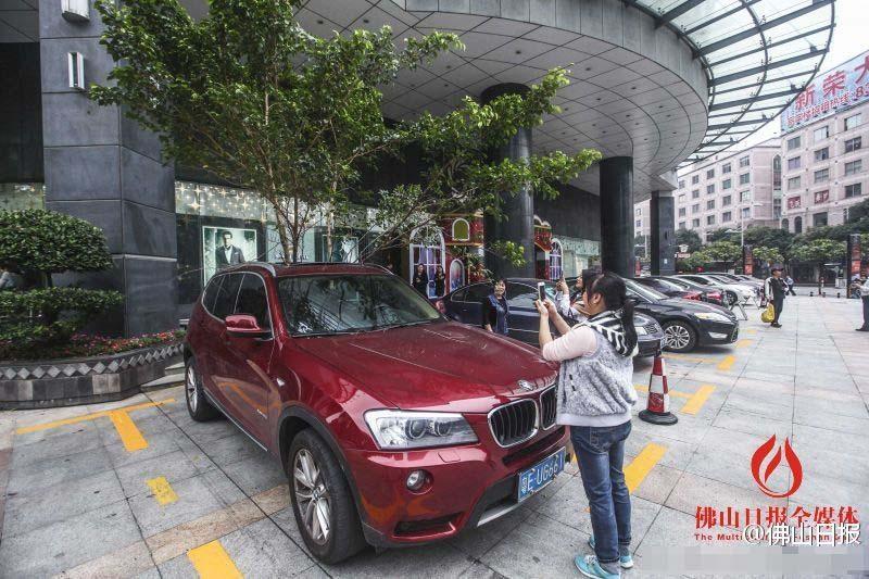 一輛停在停車位上的寶馬轎車，被墜落的樹枝砸中，樹枝徑直插入車內，現場引發不少市民圍觀拍照。