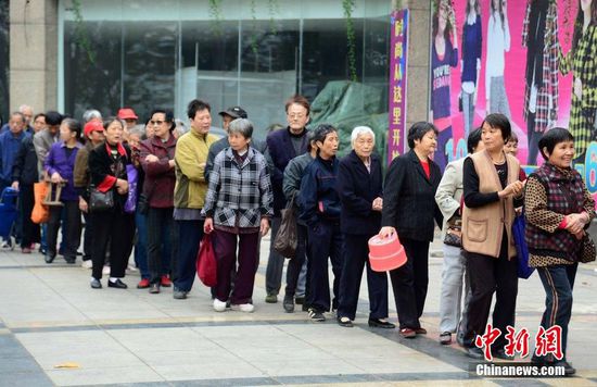 圖為10月28日，在江西九江市一家羊絨皮草服裝服飾博覽會現(xiàn)場，老人們正在頂著寒風排隊等待領取10元代金劵。