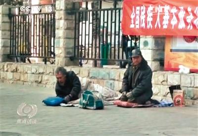 工人體育場北路，兩位乞討者路邊乞討，并輪流扮成“病人”（躺地者）。 央視截圖